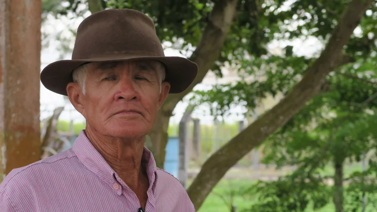 Portrait: Älterer Mann mit Hut steht unter einem Baum