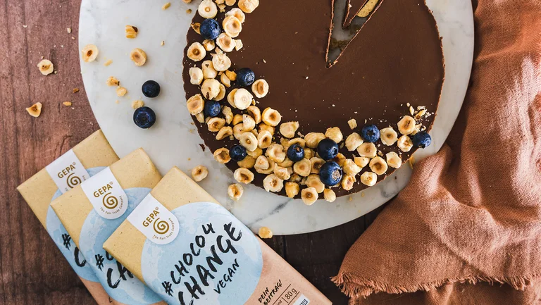 Schokotarte von oben mit N&uuml;ssen darauf, daneben zwei Packungen vegane Dattelschokolade