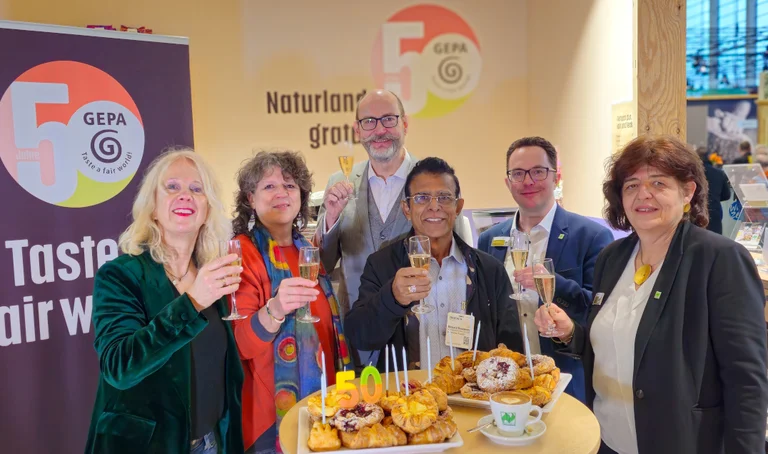 Barbara Schimmelpfennig (GEPA-Pressesprecherin), Andrea Fütterer (GEPA-Leiterin Abteilung Grundsatz und Politik), Peter Schaumberger (GEPA-Geschäftsführer), Bernard Ranaweera (Präsident von GEPA-Handelspartner SOFA, Sri Lanka), Wilhelm Heilmann, Geschäftsführer Naturland Zeichen GmbH und Karin Romeder (Mitglied der Geschäftsleitung bei Naturland Zeichen GmbH) mit Sekt auf der BIOFACH 2025