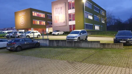 GEPA-Geb&auml;ude mit Parkplatz in Wuppertal nach Einbruch der Dunkelheit. Das Geb&auml;ude ist orange beleuchtetl.