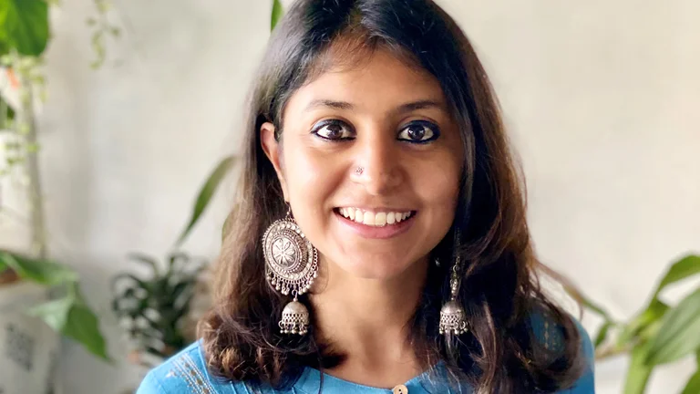 Porträtfoto von Ashwini Sashidhar. Sie lächelt offen in die Kamera, trägt auffallend große Ohrringe sowie ein Nasenpiercing.