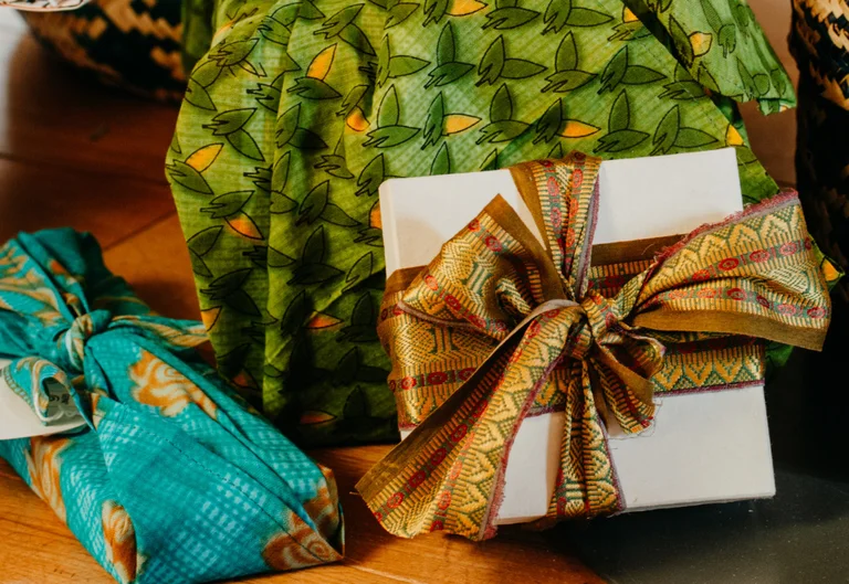 Symbolbild: Geschenkschachtel mit aufwändiger goldfarbener Schleife