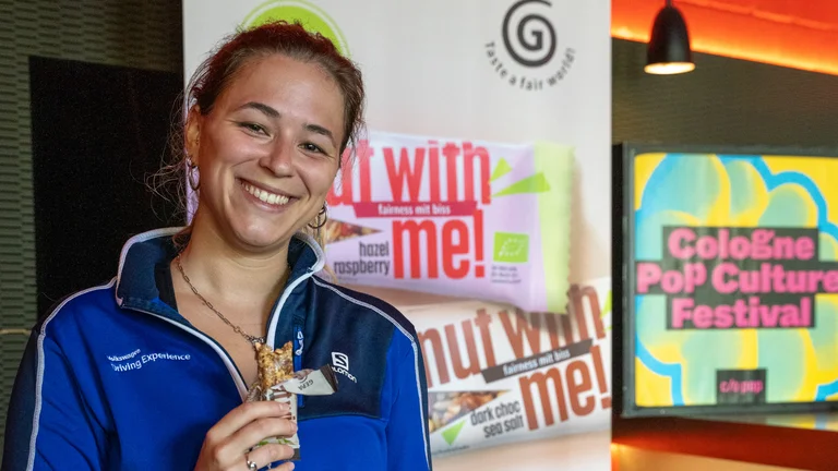 Frau in Sportkleidung mit GEPA-Riegel in der Hand. 