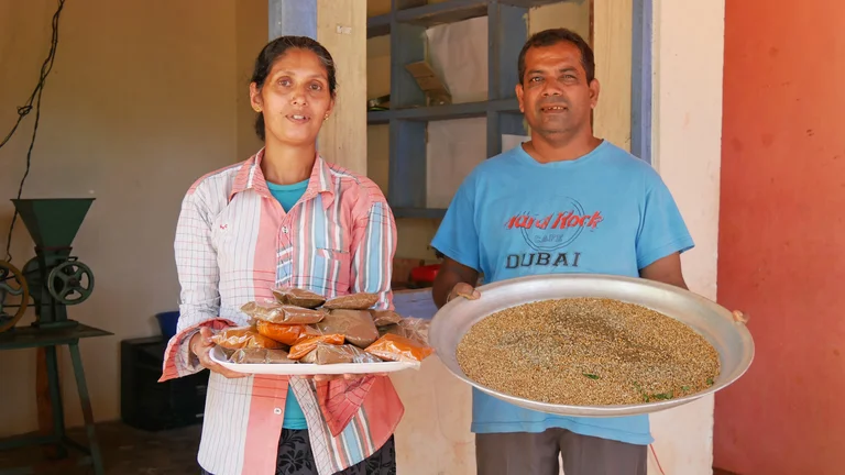 Sumithra und Gamini stehen nebeneinander, jeder ein Tablett voller Gew&uuml;rze in der Hand.
