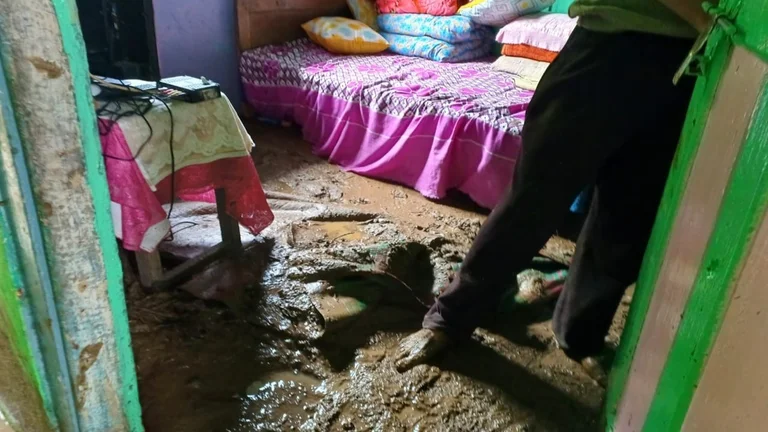 Blick in ein Zimmer mit von Schlamm bedecktem Fu&szlig;boden. Jemand steht barfu&szlig; im Schlamm.