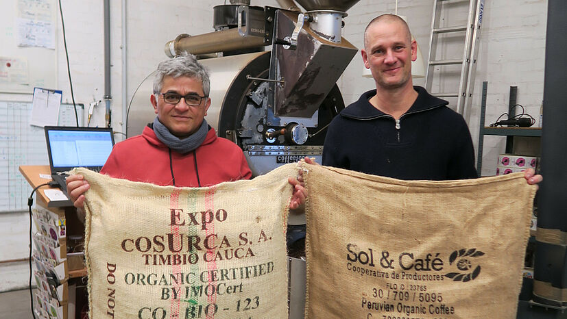 Kleber Cruz Garcia, GEPA-Einkaufsmanager Kaffee (links), und Andreas „Pingo“ Felsen, Gründer von Quijote Kaffee, mit Kaffeesäcken von den GEPA-Kaffeepartnern COSURCA (Kolumbien) und Sol y Café (Peru), deren Rohkaffee im Kooperationsprojekt X-Roast-Kaffee enthalten ist. | Foto: GEPA - The Fair Trade Company / K. Henkel