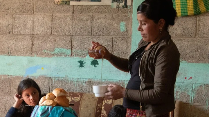 Frau gie&szlig;t Honig aus einer Flasche in eine Tasse