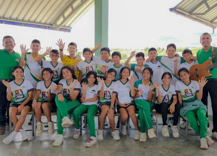 Eine peruanische Schulklasse und zwei Betreuer winken in die Kamera