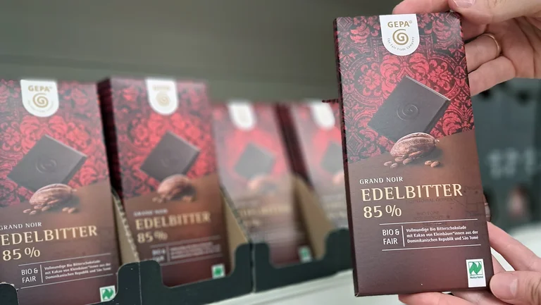 Eine Schokoladentafel Edelbitter 85% wird in die Kamera gehalten, darauf zu sehen ist das Naturland-Siegel.