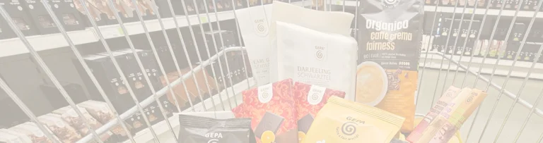Einkaufswagen gef&uuml;llt mit verschiedenen GEPA-Produkten. Im Hintergrund stehen in Regalen weitere GEPA-Produkte