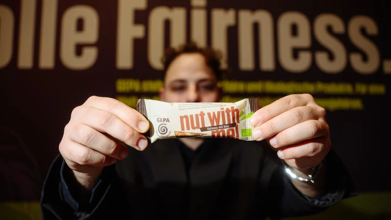 Neuer GEPA-Nussriegel &ldquo;nut with me!&rdquo; wird in die Kamera gehalten.