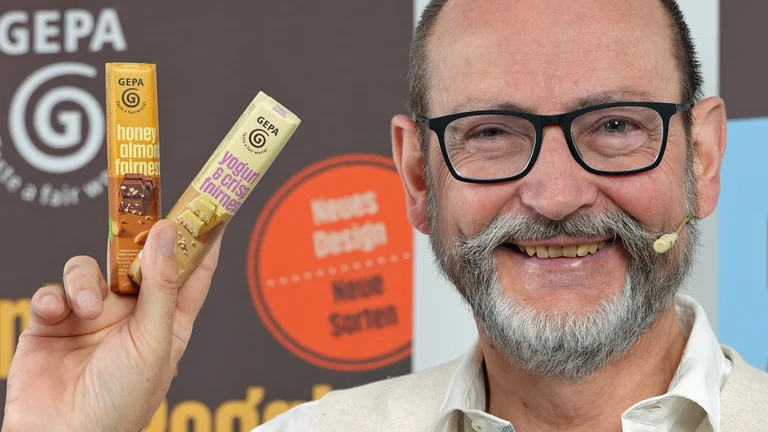 Peter Schaumberger mit zwei GEPA-Schokoriegeln in der Hand.