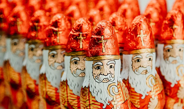 Nahaufnahme von vielen Schoko-Nikoläusen, die in Dreiecksform aufgestellt sind und den Betrachter anblicken