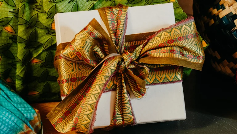 Symbolbild: Geschenkschachtel mit aufwändiger goldfarbener Schleife