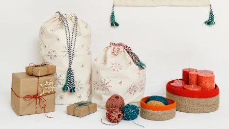 Arrangement aus Geschenken in braunem Papier, Geschenkbeuteln aus Stoff, Kordeln, K&ouml;rben und Kerzen