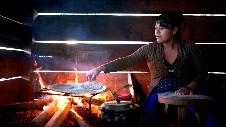 Frau in einer Holzh&uuml;tte bereitet Tortillas &uuml;ber einem Holzfeuer