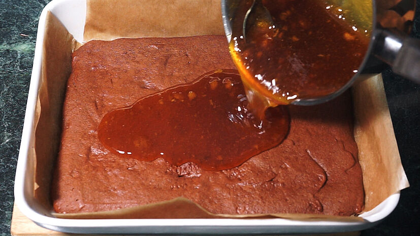 Jetzt wird die Geleeschicht vorbereitet: Dafür die Marmelade mit dem Agar Agar aufkochen und ca. 10 Minuten auskühlen lassen. Sobald die Geleemasse zähflüssig ist, kann sie auf dem Lebkuchenboden verteilt werden. Das Ganze kommt nun für zwei Stunden in den Kühlschrank.