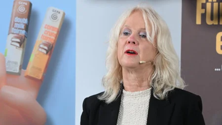 GEPA-Pressesprecherin Barbara Schimmelpfennig spricht mit Ansteckmikrofon vor GEPA-Bannern.