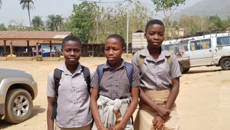 Drei Sch&uuml;ler*innen auf einem Schulgel&auml;nde in Togo