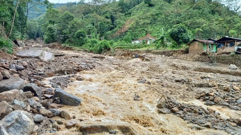 Br&auml;unliche Wassermassen flie&szlig;en an H&auml;usern einer indischen Siedlung vorbei.