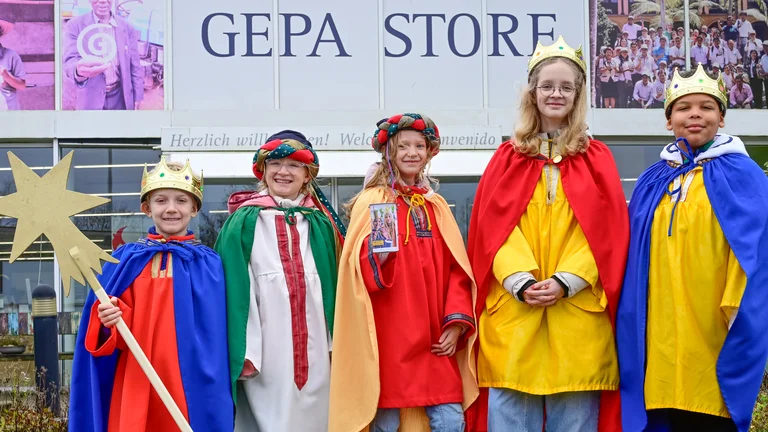 F&uuml;nf Sternsinger-Kinder stehen vor dem Eingang des GEPA-Stores in Wuppertal und l&auml;cheln in die Kamera.