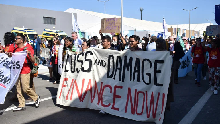 Gruppe von Demonstrierenden marschiert. Im Vordergrund hält eine Gruppe ein Banner mit der Aufschrift: "Loss and damage. Finance now"
