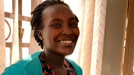 Portrait einer Frau vor einem Fenster, durch das Sonne scheint.