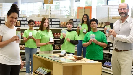 Celia Sasic und GEPA-Gesch&auml;ftsf&uuml;hrer Peter Schaumberger sowie f&uuml;nf Kinder in gr&uuml;nen T-Shirts stehen im GEPA-Store in Wuppertal. Sie alle zeigen eine oder zwei Tafeln GEPA-Schokolade #Choco4Change in die Kamera.