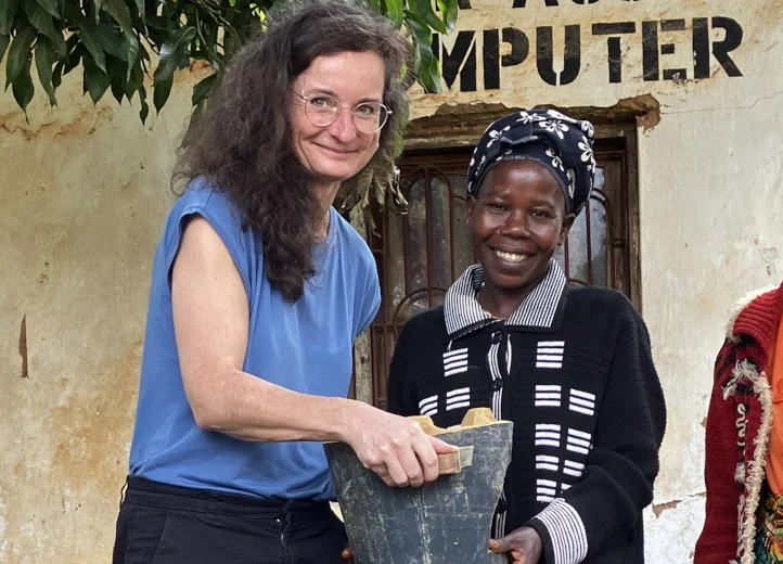 Eine Frau überreicht einer anderen vor einem Gebäudeeingang einen Kochofen.