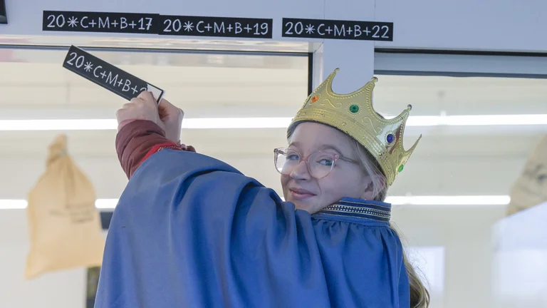 Sternsinger-Mädchen beim Aufkleben eines Segensaufklebers