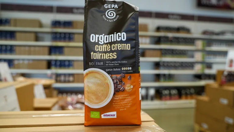 Eine Packung GEPA organico caff&eacute; crema fairness, im Hintergrund sind Ladenregale zu sehen.
