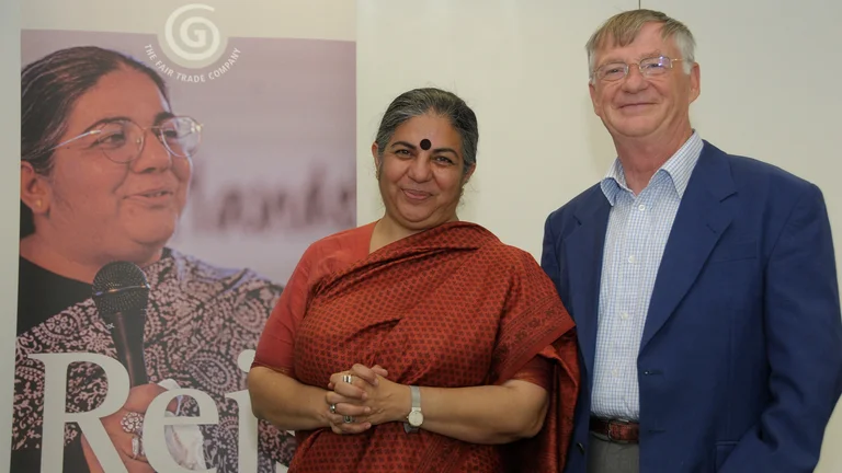 Vandana Shiva und Gerd Nickoleit l&auml;cheln in die Kamera. An der Wand h&auml;ngt ein GEPA-Plakat, auf dem auch Vandana Shiva zu sehen ist.
