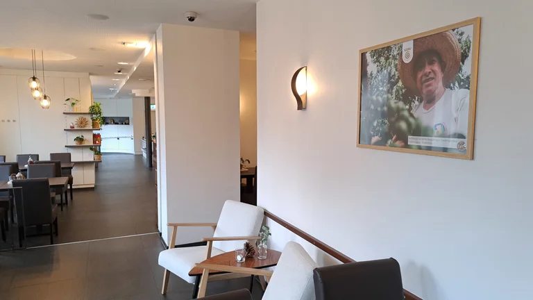 Blick in ein Café. An der Wand hängt das Bild eines Kaffeebauern mit GEPA-Logo.