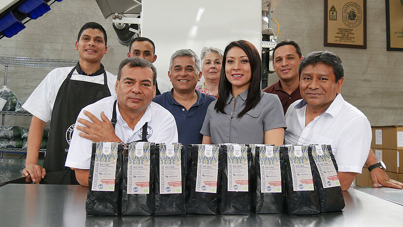 Das Team der Rösterei von FEDECOCAGUA in Palin, Guatemala, freut sich zusammen mit den beiden Besuchern von der GEPA (hinten Mitte) über den neuen Kaffee. Seit drei Jahren kann FEDECOCAGUA hier den Rohkaffee seiner Mitglieder selbst rösten, mahlen und verpacken – und dadurch mehr Wertschöpfung erzielen.