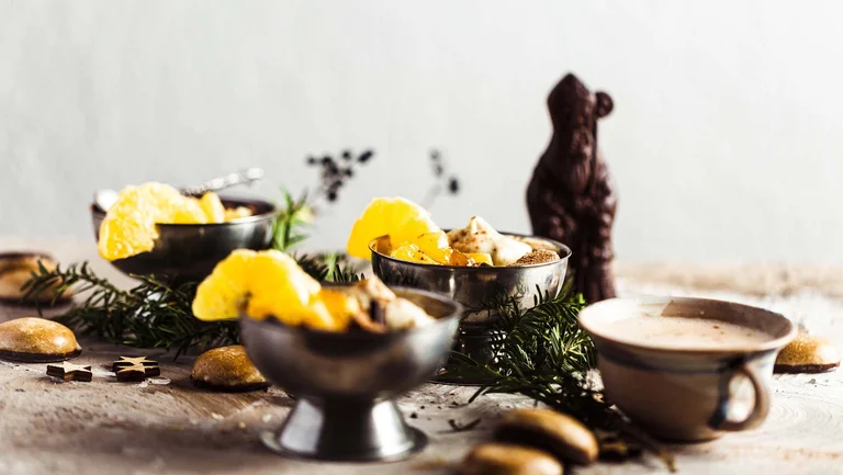 Silberschalen mit Joghurt darin, dazwischen Tannenzweise und ein dunkler Schoko-Nikolaus als Dekoration