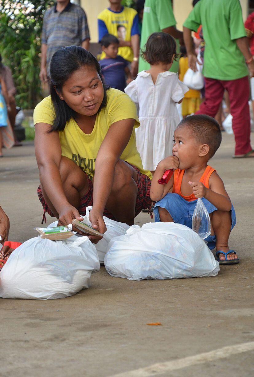Mutter mit Kind in Manapla mit ihren Hilfspaketen.