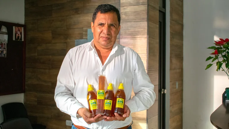 Mann in Hemd h&auml;lt Honigflaschen in der Hand