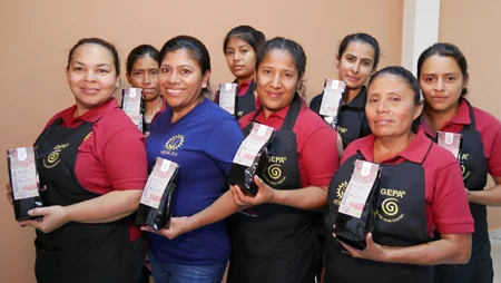 Gruppenbild von Frauen in APROLMA-Schürzen mit APROLMA-Kaffeepäckchen in den Händen