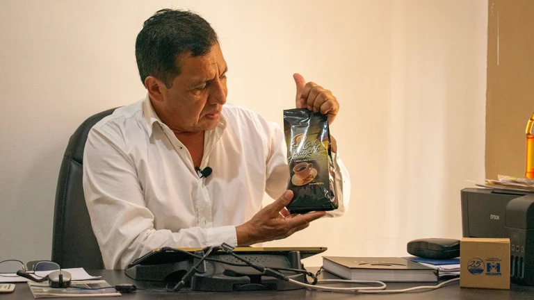 Mann an einem Schreibtisch h&auml;lt eine Packung Kaffee