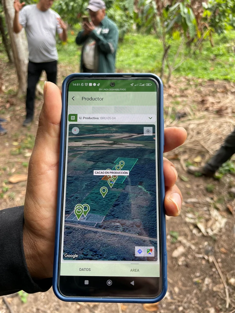 Hand h&auml;lt ein Smartphone, auf dem ein Satellitenbild und Geodaten zu sehen sind.