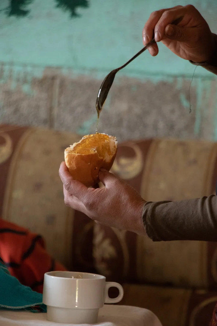 Honig flie&szlig;t von einem L&ouml;ffel auf ein Br&ouml;tchen
