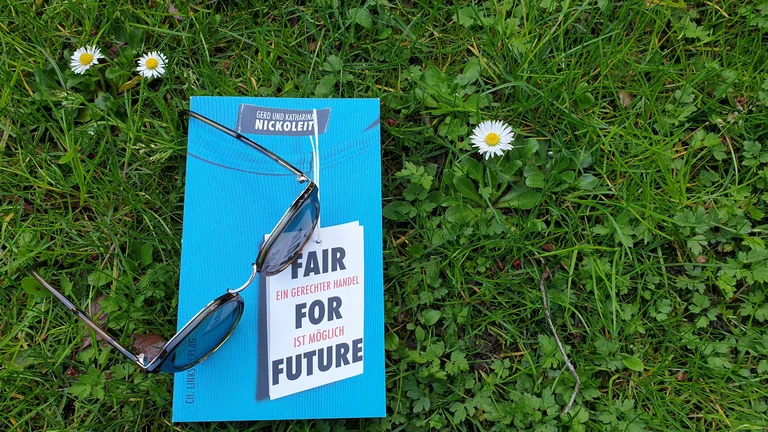 Auf einer gr&uuml;nen Wiese liegt das Buch: "Fair For Future - ein gerechter Handel ist m&ouml;glich" von Gerd und Katharina Nickoleit. Auf dem Buch liegt eine Brille.