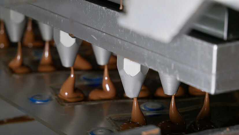 In der Gießmaschine wird die Schokolade gewichtsgenau vergossen, beim GEPA-Nikolaus sind es 65 Gramm. Die Schokoladenmasse wird zunächst in eine Formhälfte gegossen, eine zweite Hälfte wird darauf gesteckt: Und dann geht’s in die Schleudermaschine. 