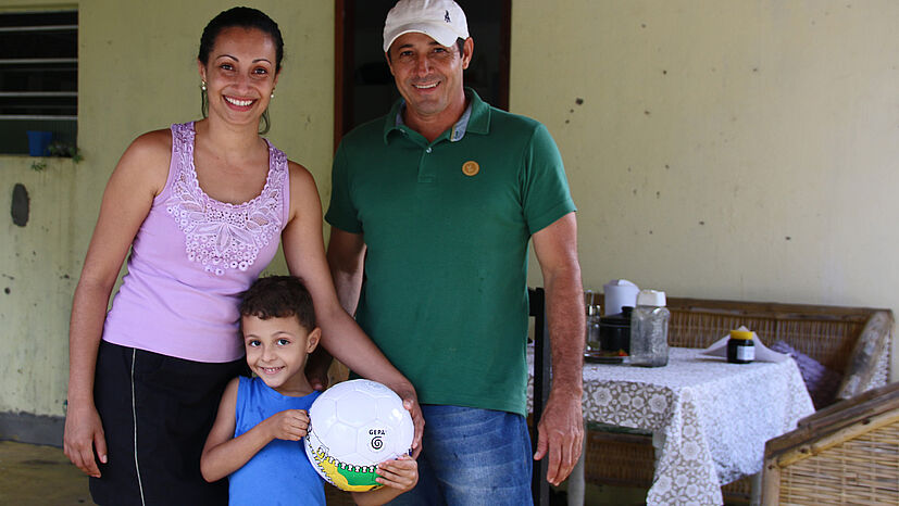 Bio-Bauer Welisson da Silva Santos ist Mitglied bei COOPEALNOR. Zusammen mit seiner Frau Daniele Evangelista da Silva baut er neben den Orangen so viele Früchte wie möglich selbst im eigenen Garten an. Seine Frau kümmert sich um das Haus und hilft bei der Ernte. Sohn Danilo ist vier Jahre alt und hält stolz einen fairen GEPA-Fußball in den Händen.