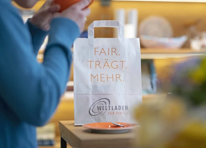 Papiertüte mit der Aufschrift "Fair trägt mehr" auf einem Tresen