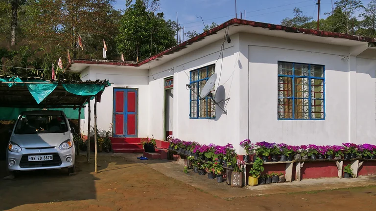 Bishnus neues Haus von au&szlig;en, man sieht auch ein Carport mit kleinem Auto.