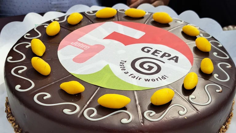 Torte mit Schokoladenüberzug mit gelben Kakaoschoten aus Marzipan und dem GEPA-Jubiläumslogo in der Mitte.
