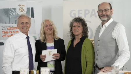 Zwei Männer und zwei Frauen stehen vor GEPA-Bannern und lächeln in die Kamera. Eine der Frauen hält Moderationskarten in Händen.