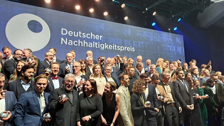 Eine gro&szlig;e Menschenmenge, alle in Abendkleidern und Anz&uuml;gen mit Preisstatuetten in der Hand. 