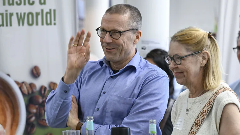 Wuppertals Oberbürgermeister Uwe Schneidewind auf einer Veranstaltung. Er hebt die Hand und lacht dabei. Neben ihm die Dritte Bürgermeisterin der Stadt Wuppertal Dagmar Liste-Frinker